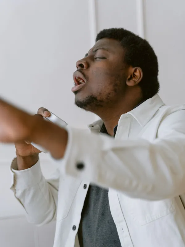 Man in a white jacket singing with his arm stretched out and his eyes half closed
