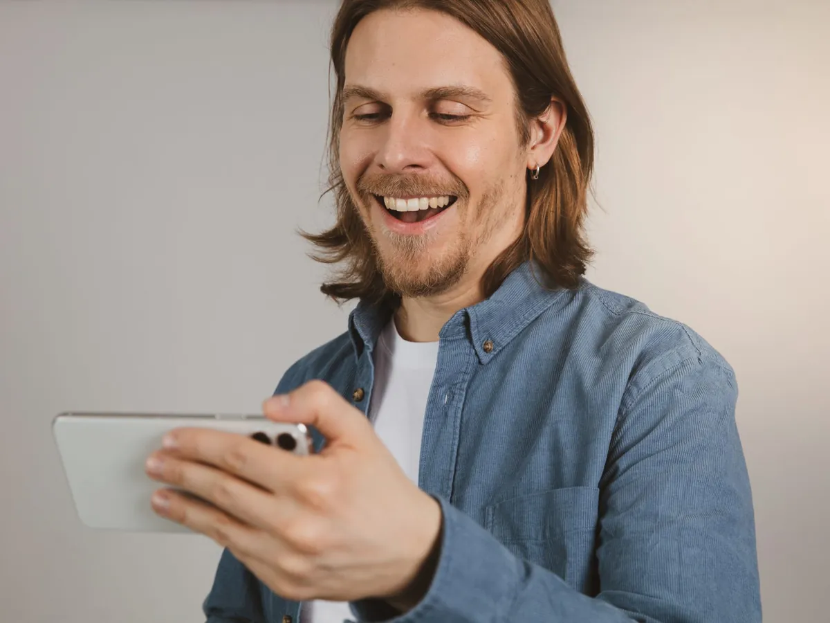 Smiling man looking at his phone, happy with the result on the screen