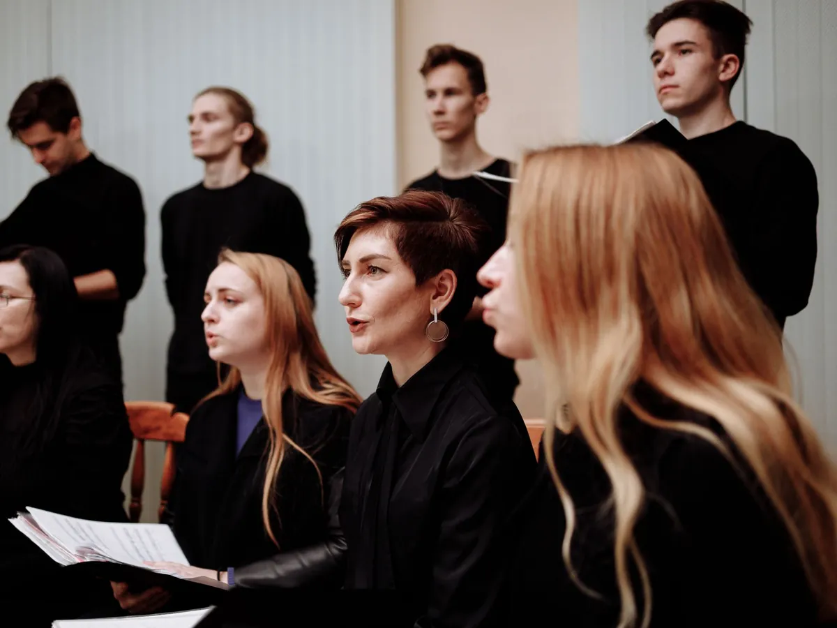 Men and women of different ages singing together in a choir, sheet music in hand